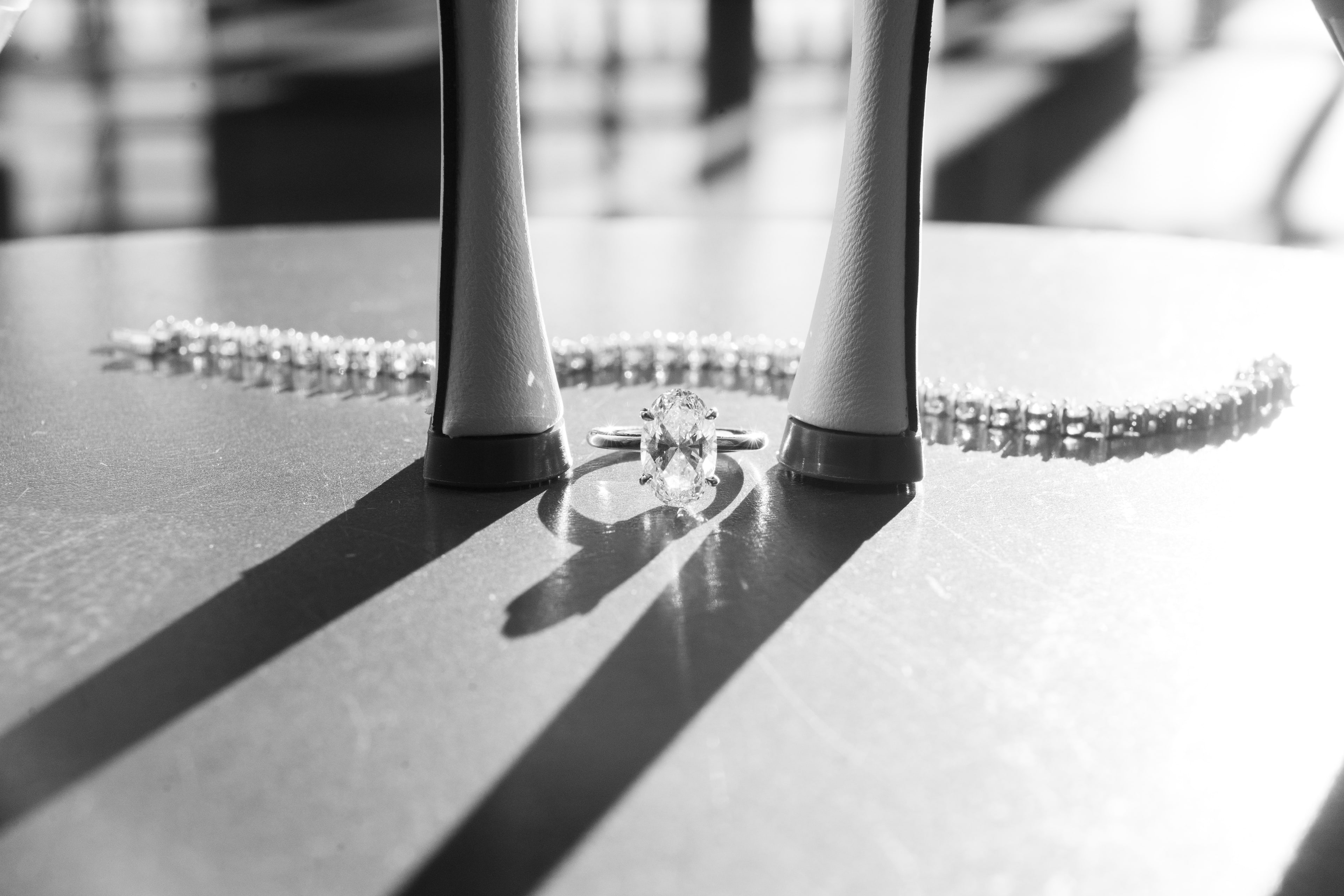Bridal heels framing a diamond ring with a tennis bracelet on a marble table — black and white editorial