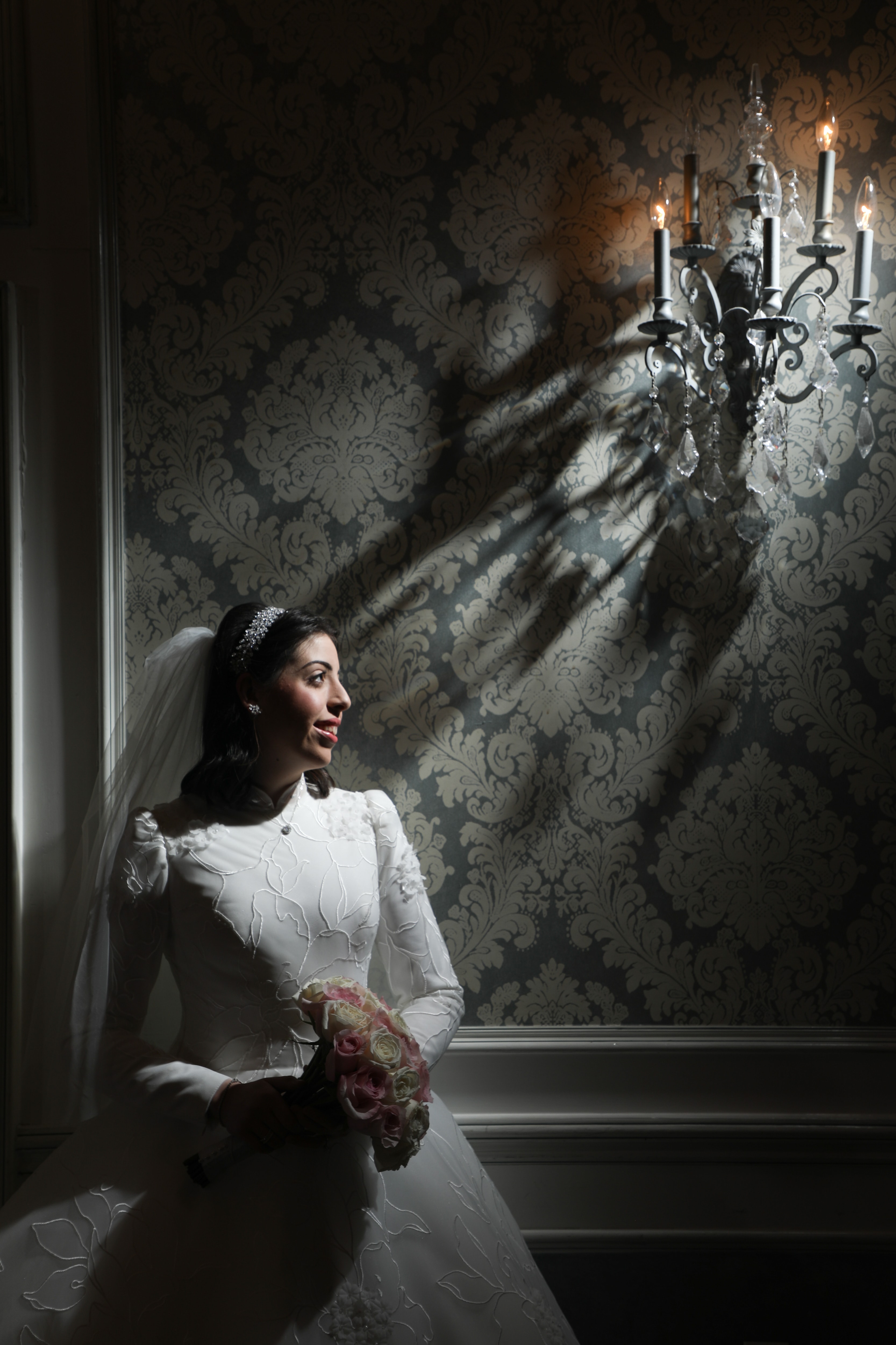 Bride against damask wallpaper with chandelier shadow